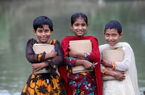 Three girls smile while standing in front of the open deck holding their books at the boat school, Shanto Nagar, Singara, Natore. 03 November 2012. Photo: Abir Abdullah/SSS